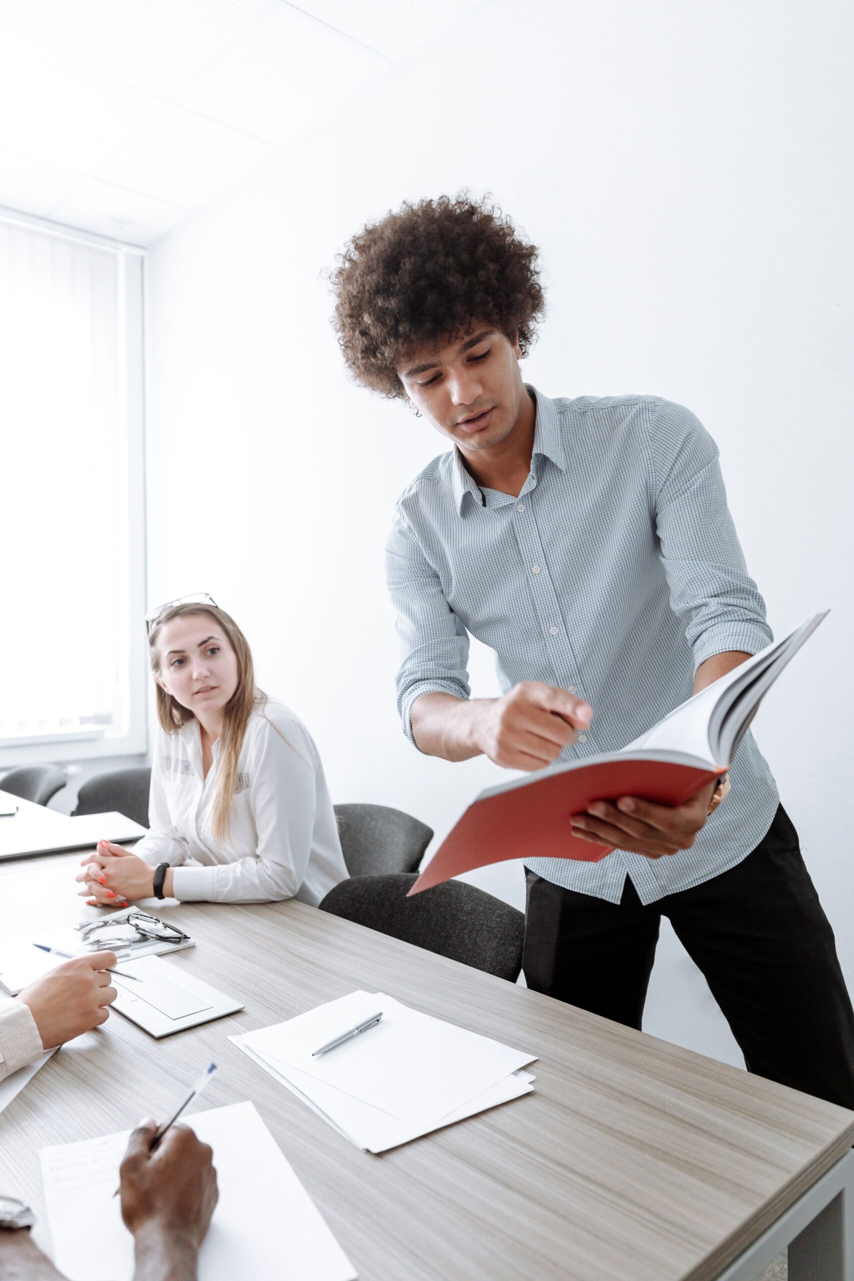 A young man in an apprenticeship presents findings from a folder to his colleague.